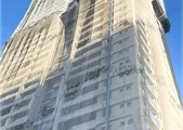 Edifício alto em obras, envolto em tela de proteção com a marca Sousa Andrade.
