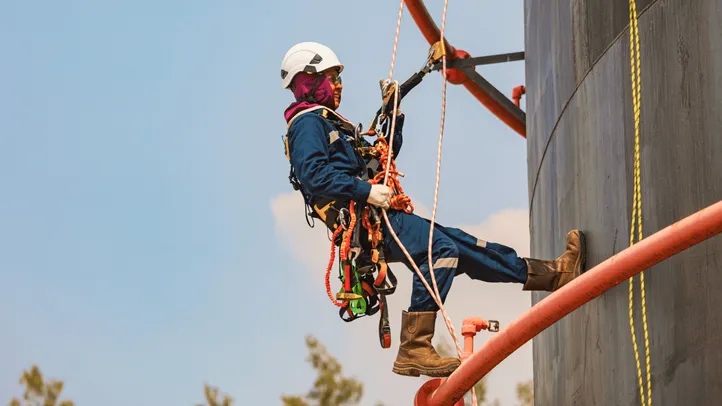 Homem executando trabalho em altura, utilizando EPIs